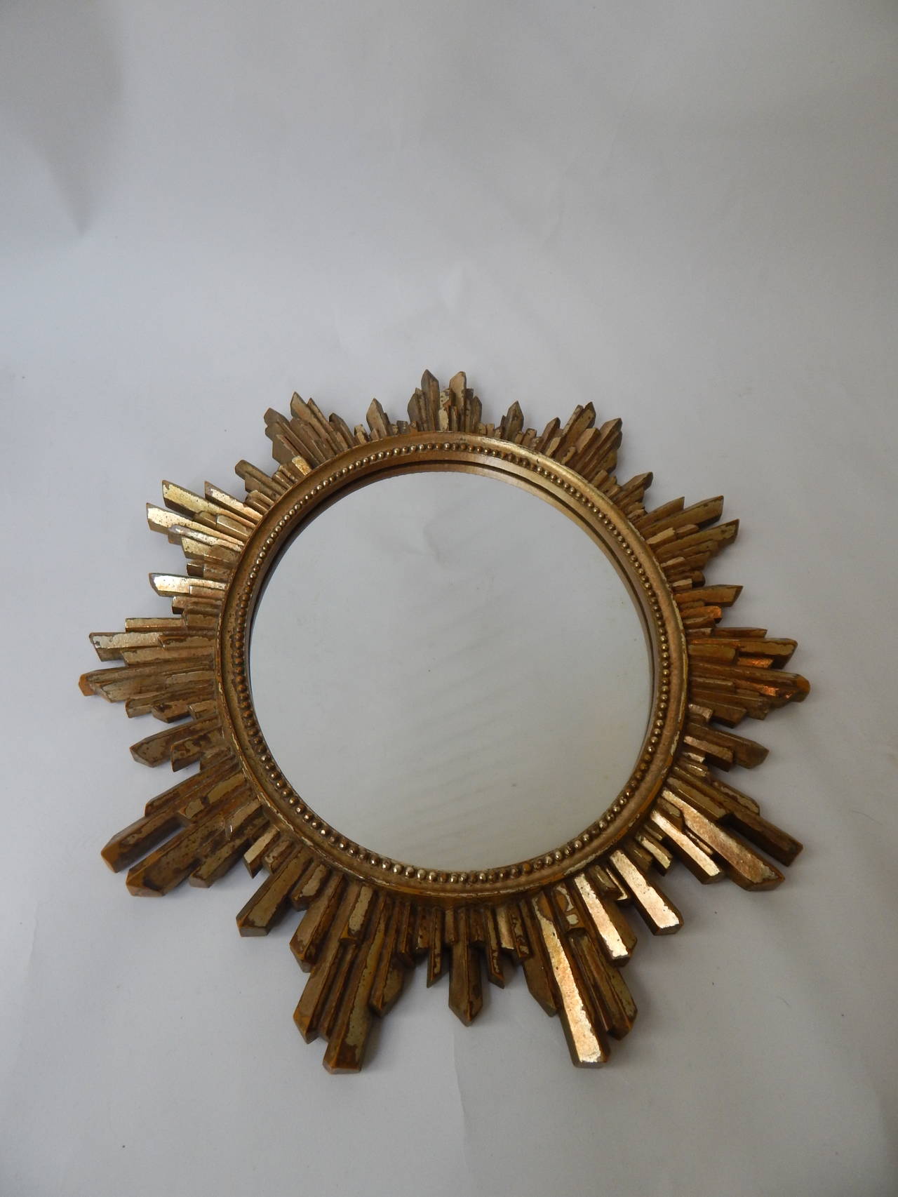 Italian gilded wood sunburst oval mirror. Bead molding around mirror suggests deco era. Leather back. Leather stand on back was removed over the years but the hanging wall hook remains in tact. See photo.