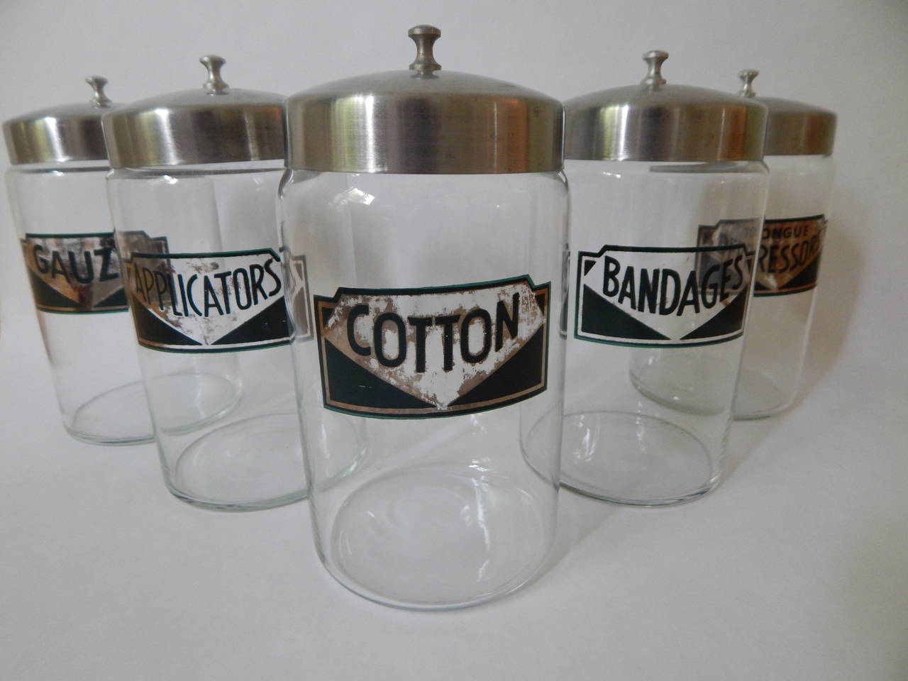 Vintage Apothecary jars from the 1930s or 1940s used in doctors office. Glass with stainless or aluminum lids. Excellent condition with exception to some wear to the silver colored part of labels.