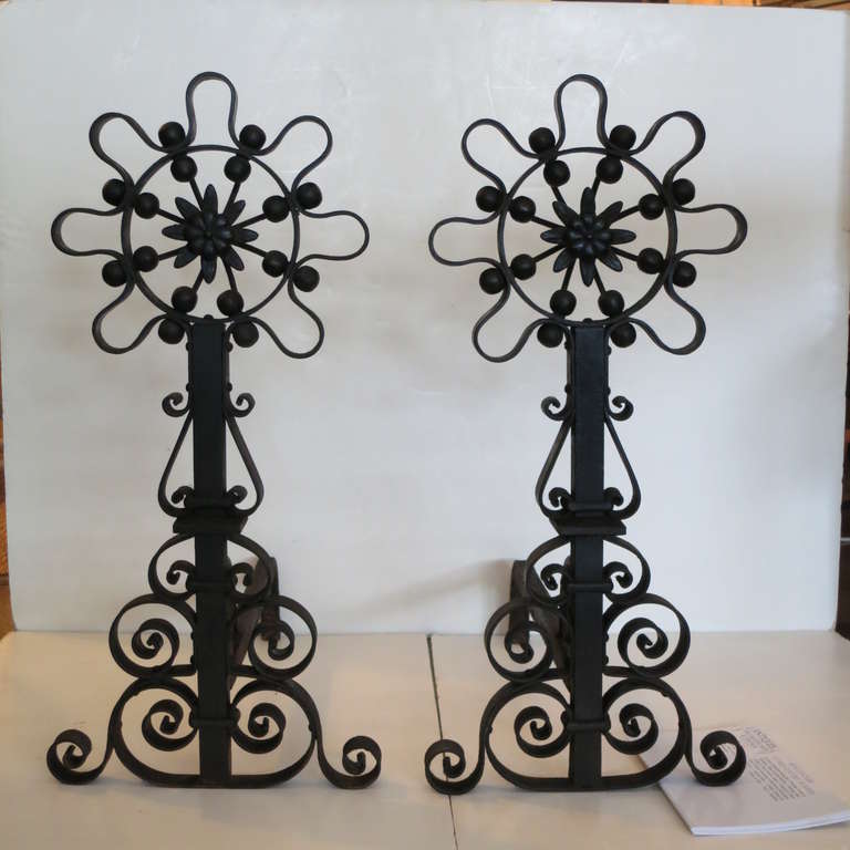 A pair of handwrought iron andirons with sculptural openwork and strong details.