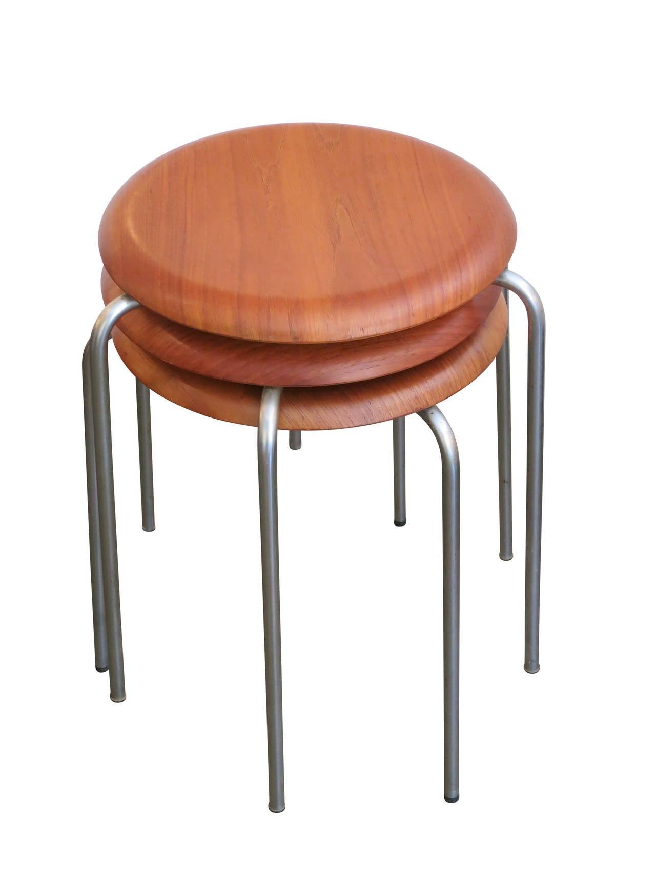A set of 3 Series 7 stools designed by Arne Jacobsen for Fritz Hansen in 1955. The slightly curved teak seat rounds at the edge and is supported by three chromed steel legs. Stackable for storage or display.