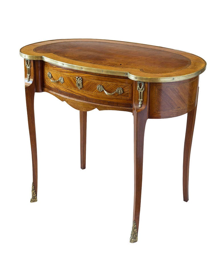 An elegant kidney-shaped one drawer table with a tooled leather top. This table is made from walnut, kingwood and other exotic woods and has ormolu mounts.