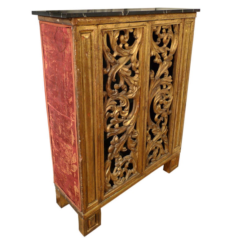 Italian gilt wood cabinet with carved doors and antique, fabric covered panels at sides.  The faux marble wood top and feet are later additions. The interior allows for two shelves.