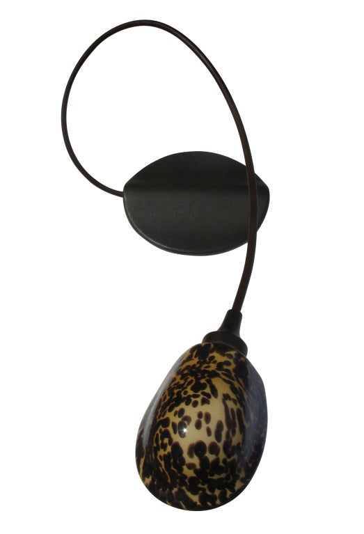 This lamp has a beautiful, sinuous design. The blown glass tortoise shade sits atop a gracefully arcing arm. Both the arm and base are of patinated metal.  The glass shade articulates side-to-side and the arm is sensored for on/off touch capability.