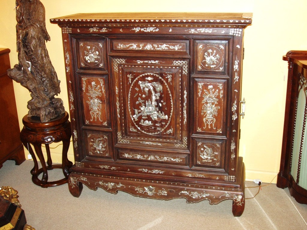 Beautiful oriental rosewood cabinet with mother of pearl inlay. Both ends open for storage. Shrinkage crack in door
