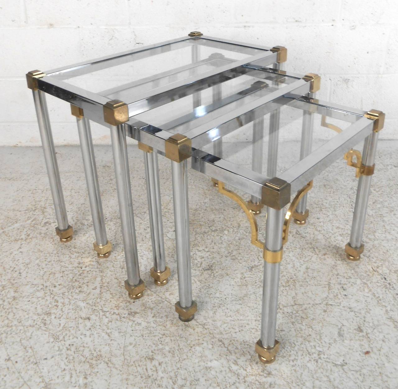 Ensemble de trois tables gigognes en chrome poli avec accentuation en laiton. Fabriqué à la manière de la Maison Jensen, avec des plateaux en verre.

(Veuillez confirmer l'emplacement de l'article - NY ou NJ - avec le concessionnaire).