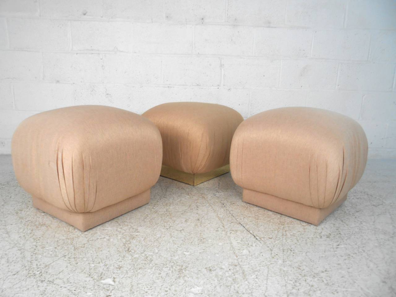 Mid-Century modern ottomans in the style Karl Springer. Pair have fabric bases, one is lined with brass platting. Great for extra seating or in front of your lounge chair.

(Please confirm item location - NY or NJ - with dealer)