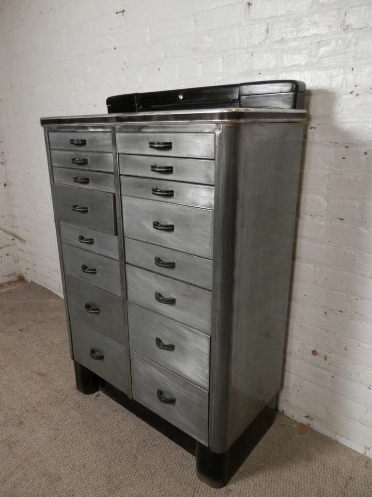Bold metal cabinet used in the early century as a dental storage unit. Newly striped and lacquered for a handsome and stylish bare metal finish, nicely offsetting the black detailing. Great for modern use as a file cabinet or bedroom