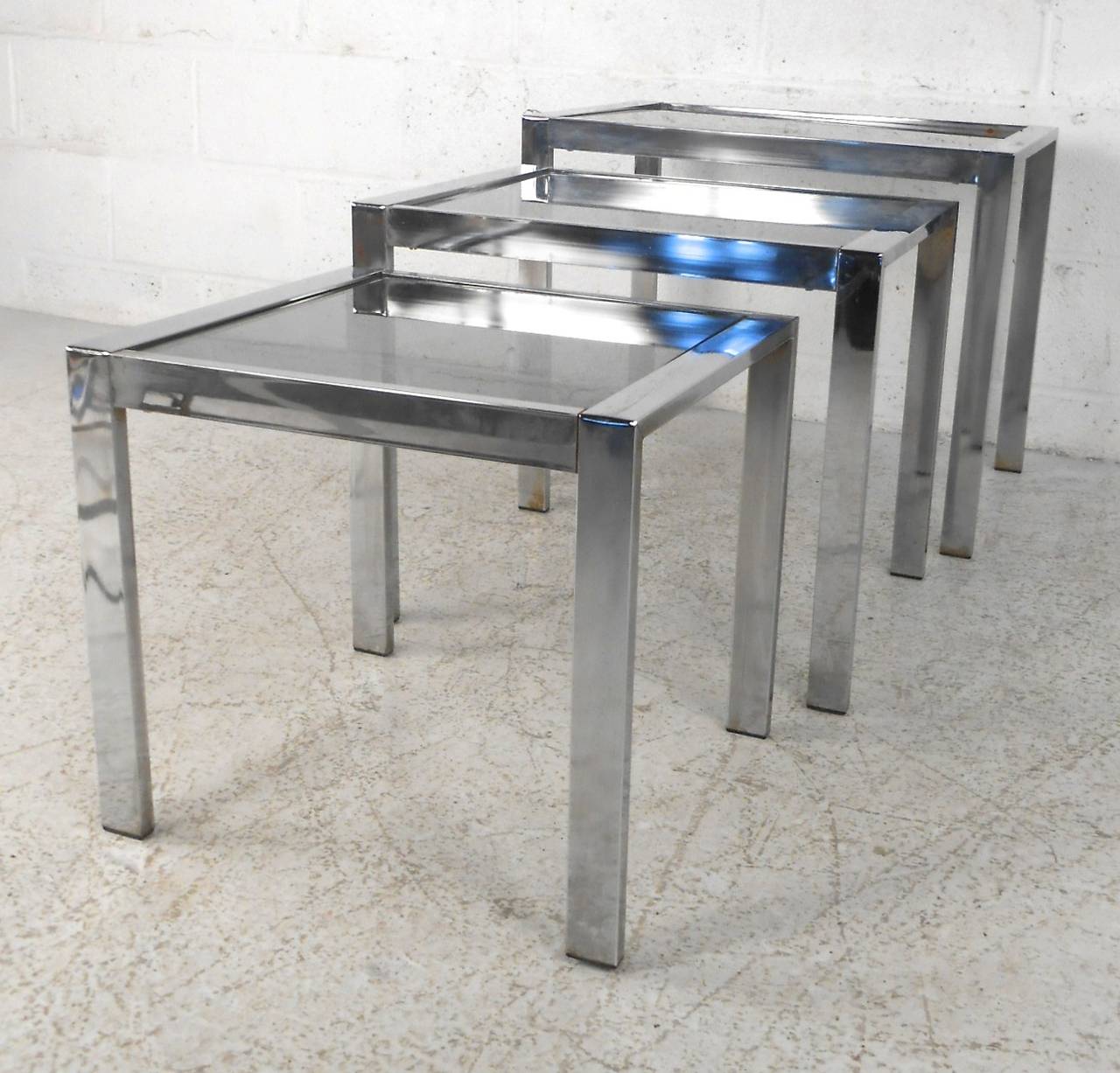 This set of three chrome tables feature vintage smoked glass tops set in sturdy nesting frames. Perfect for occasional use at home or office, please confirm item location (NY or NJ). Dimensions from 24-17 inches wide, 15-19 inches high.