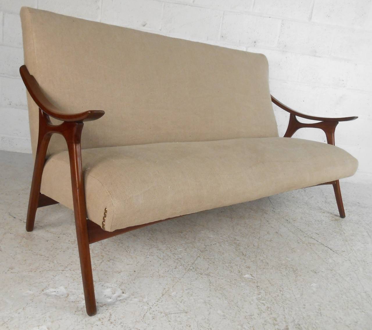 This unique midcentury sofa features stylish curved armrests, original studded upholstery, and a unique finish. Please confirm item location (NY or NJ).