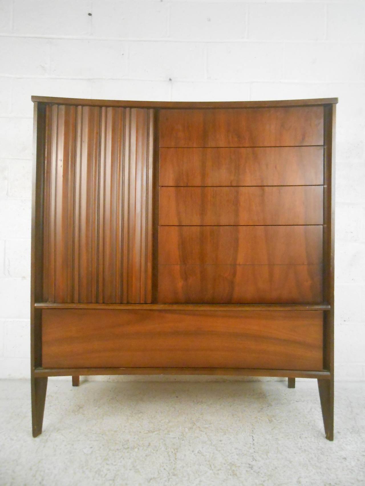 Unique style American dresser with sculpted door and bowed front. Nine total drawers, tapered legs, walnut grain. Designed by Unagusta for their 'Strata' series.

(Please confirm item location - NY or NJ - with dealer)