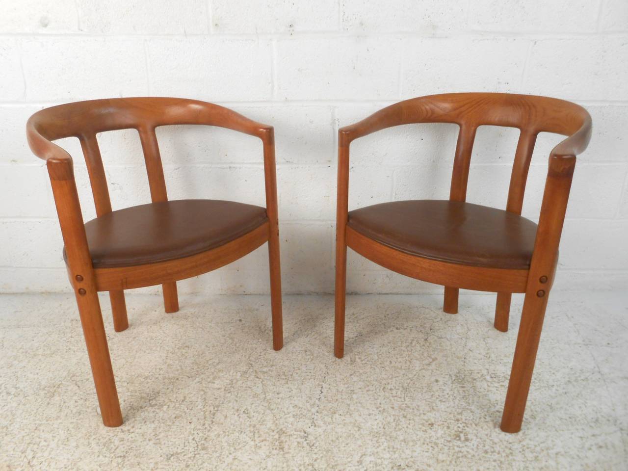 Pair of impressive Danish armchairs with rounded backs, made by L. Olsen & Son with great craftsmanship. Great detail to the sculpted backs, tight dovetailing with rich teak grain throughout and leather seats. Similar to the famous round chair by