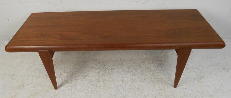 Scandinavian Modern teak coffee table with thick banded top and uniquely shaped tapered legs. Please confirm item location (NY or NJ) with dealer. Please confirm item location (NY or NJ) with dealer.