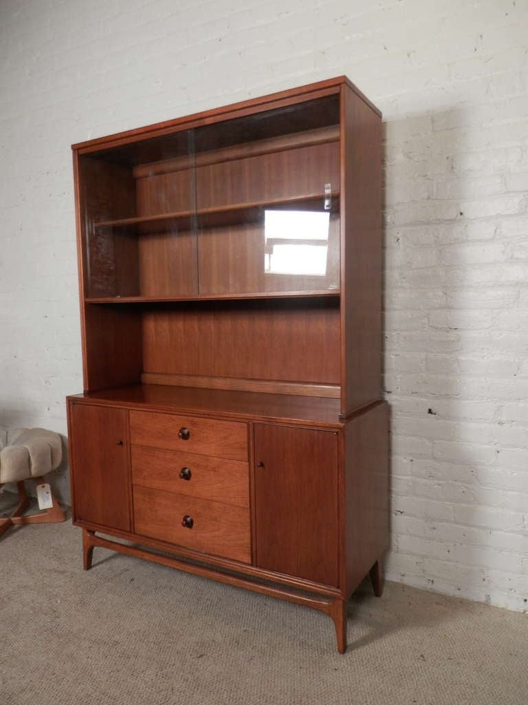 Vintage modern credenza and glass front hutch by Thomasville with handsome sculpted rosewood pulls, elegant legs and wide glass sliding doors on a removable top. Two side cabinets and three middle drawers. Well made and especially