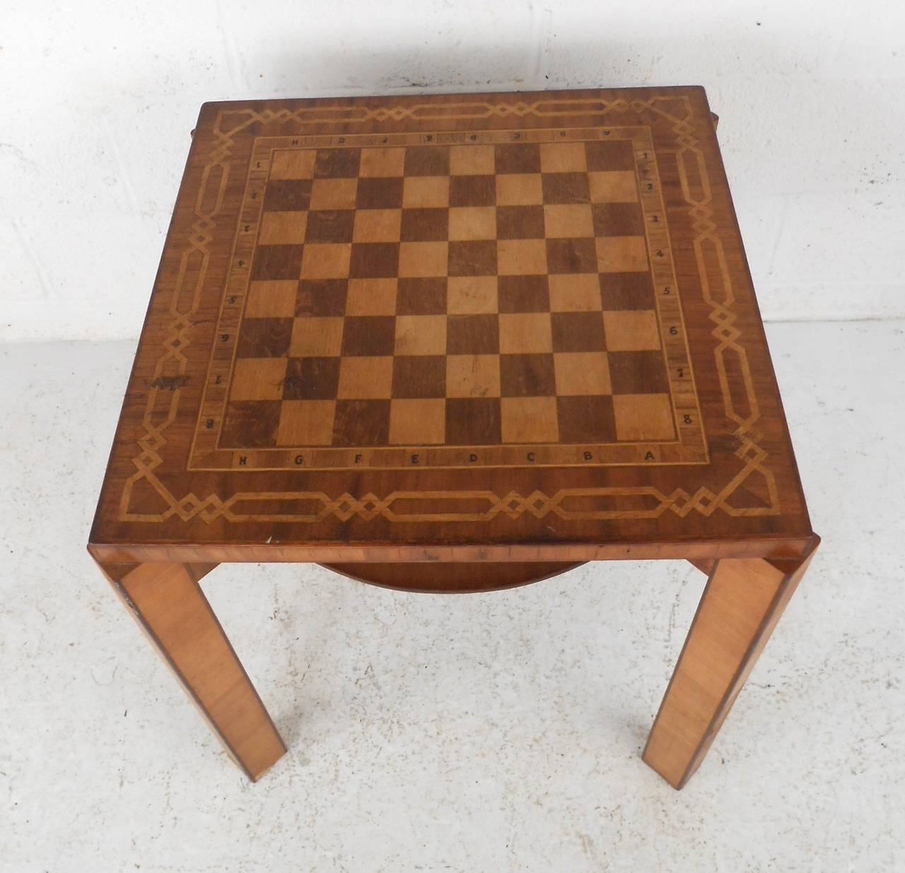 This vintage table features a mixture of hardwood complete with decorative inlay to make for a rustic and unique chess table. With secondary shelf for storage, this piece is perfect for decor or gaming. Please confirm item location (NY or NJ).