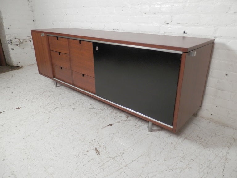 Classic long cabinet by famed Mid-Century designer George Nelson. 
Left to right: Locking cabinet with shelving, sliding door reveals five pull-out drawers, one with file hang rails, right side locking storage cabinet with shelving. Note that keys