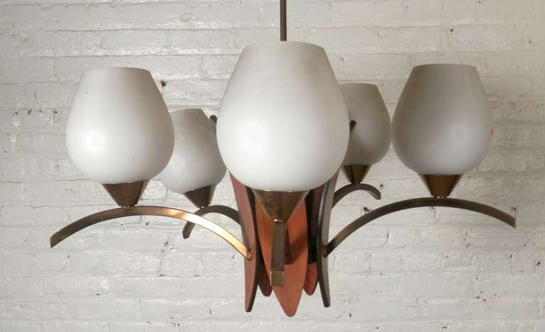Sophisticated and simple Sixties era five globe chandelier. Curved teak center and accenting arched brass arms holding five white glass globes. Delicate modern design.

(Please confirm item location - NY or NJ - with dealer)
