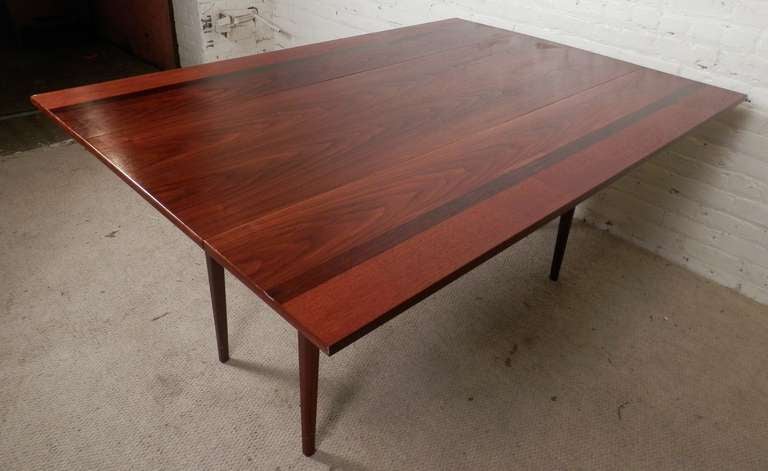 This is a table you don't cover up!  Stunning rosewood and teak inlay grains, slender cone legs and easily adjustable leaves. Can comfortably sit 6-8 people, or collapse for use as an entry console.

Open - 42