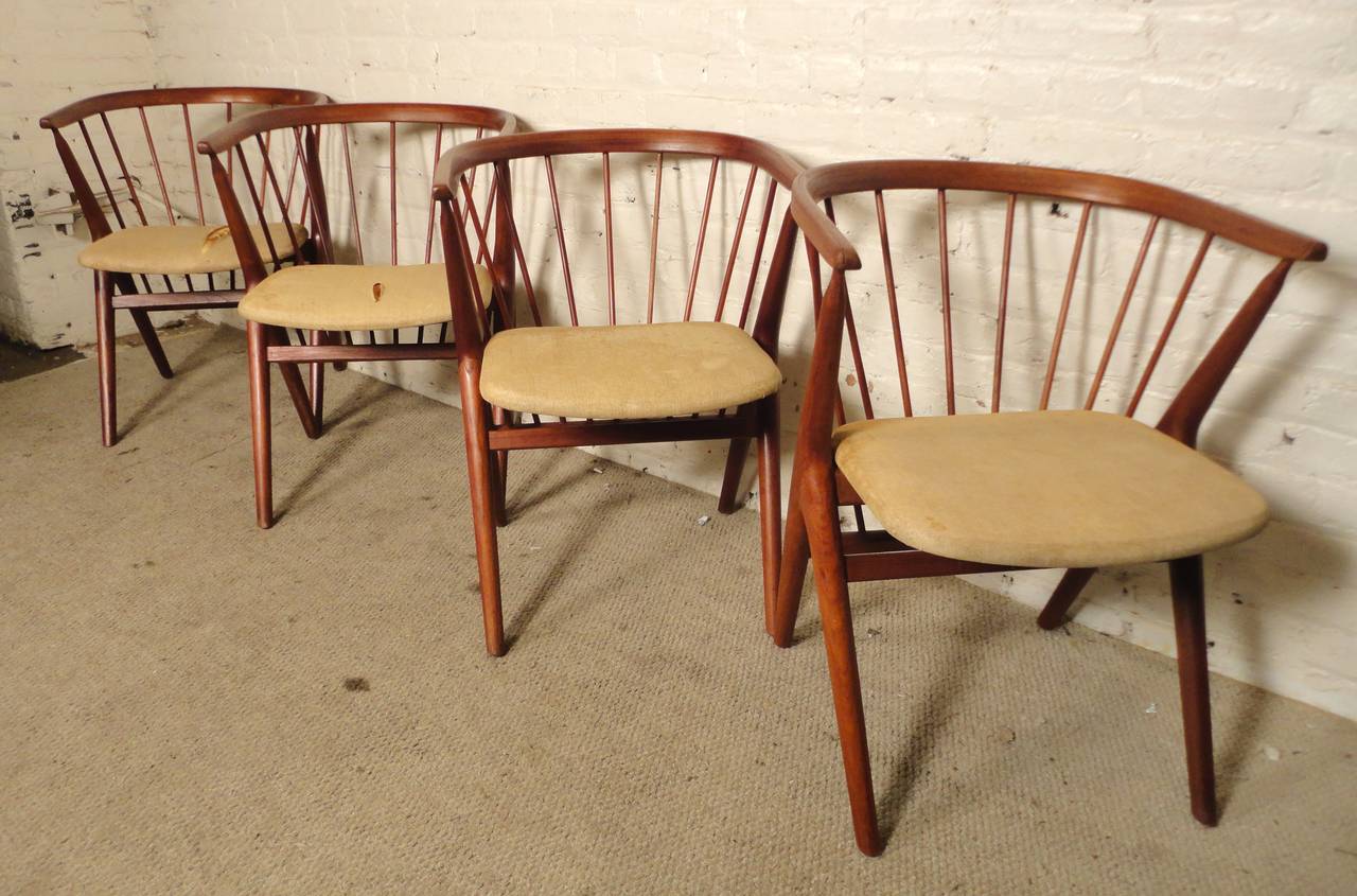 Elegant set of four dining chairs by Danish designer Helge Sibast. Hand carved solid teak wood with sculptural design, spindle detail and rounded back. The cushions have a 