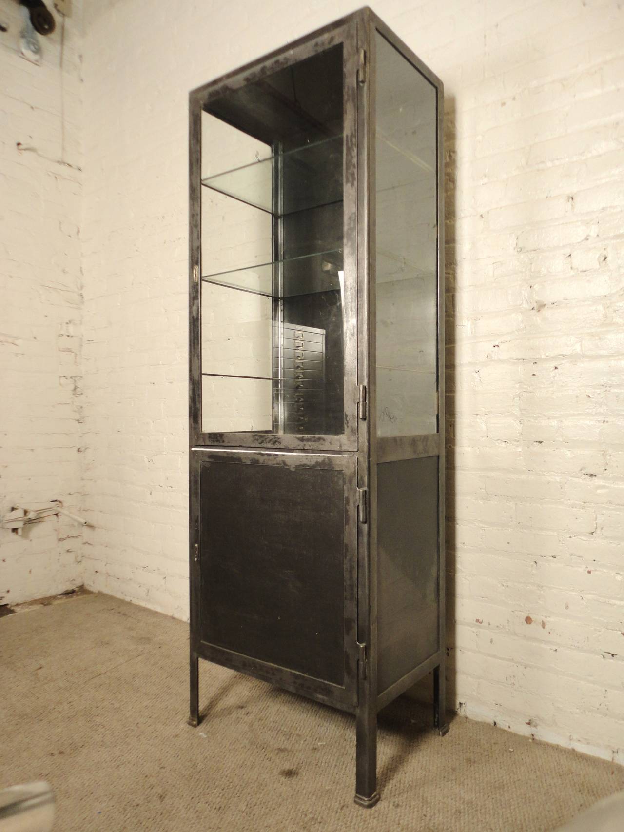 Vintage hospital cabinet, made of steel with glass front and sides. Large top exposed cabinet with two glass shelves, bottom concealed cabinet with shelf. Makes a great kitchen pantry or bathroom storage cabinet.
Working key for bottom