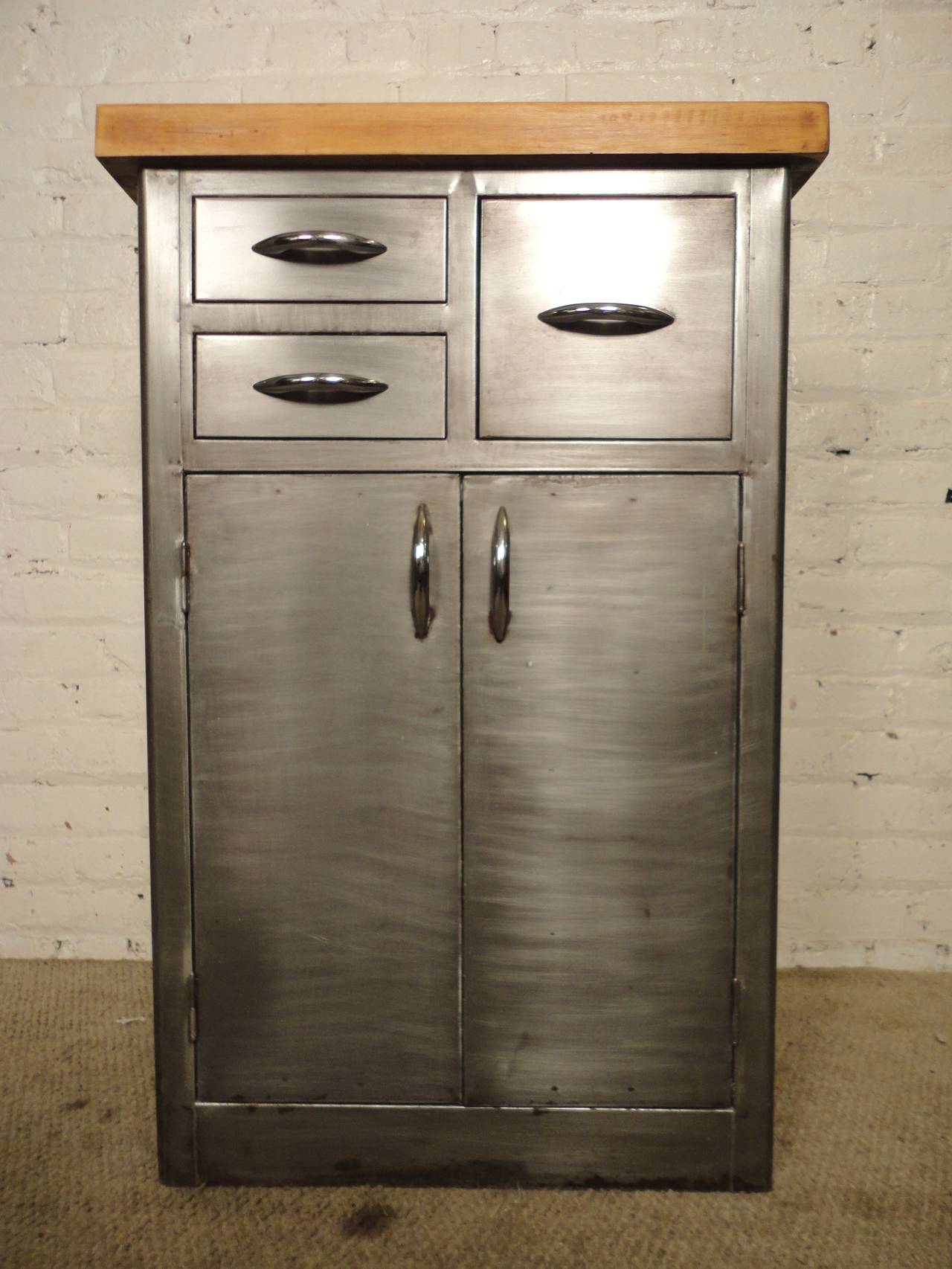 Cool metal cabinet with a thick wood block top. Stripped to a handsome bare metal look. Three drawers and double door cabinet. Great for kitchen or bathroom storage.

(Please confirm item location - NY or NJ - with dealer)