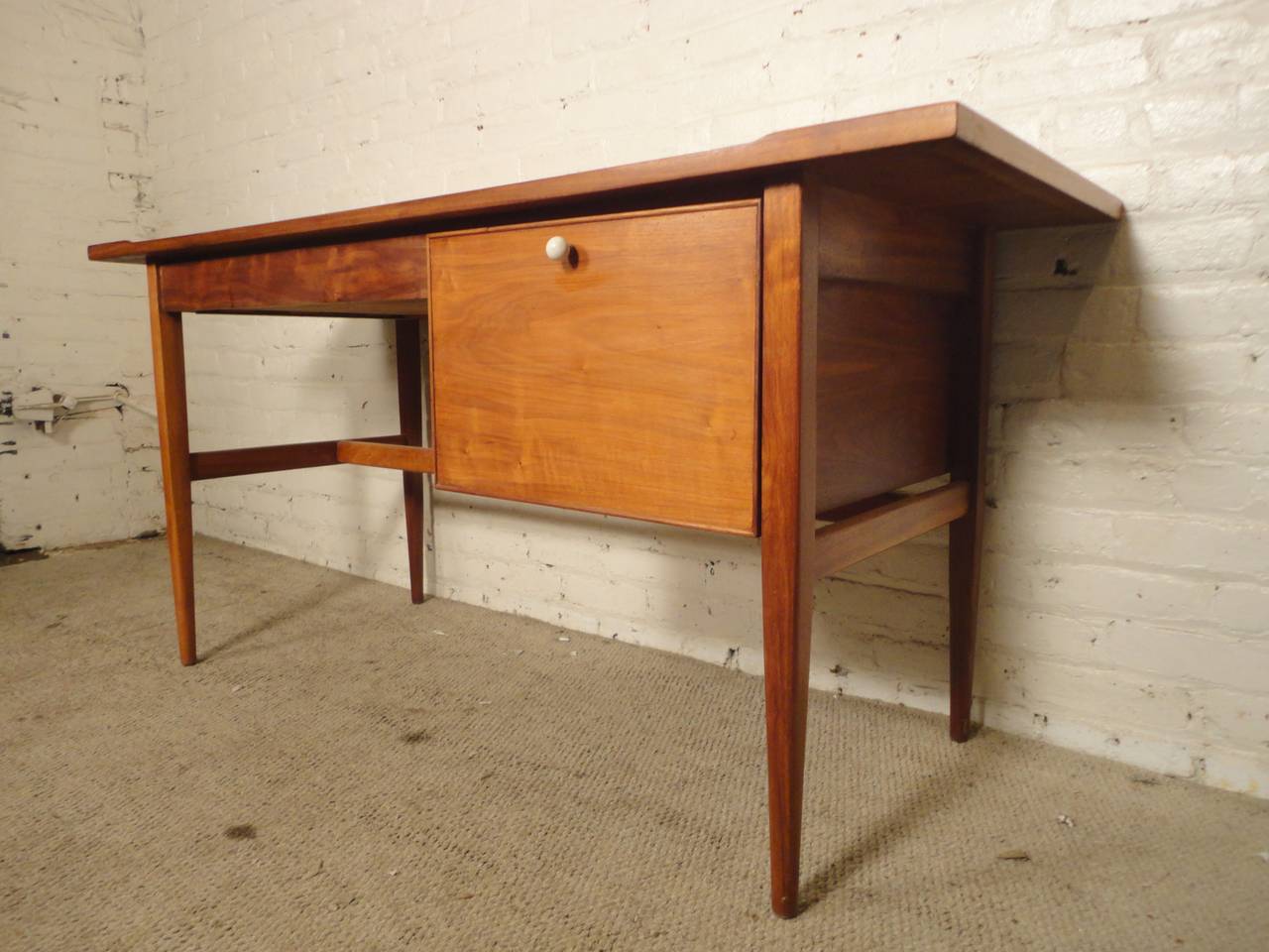 Vintage modern writing desk designed by Kipp Stewart for Drexel. Beautiful walnut grain with two drawers. Simple lines, sculpted legs, curved edge and finished back.
Kneehole: 27