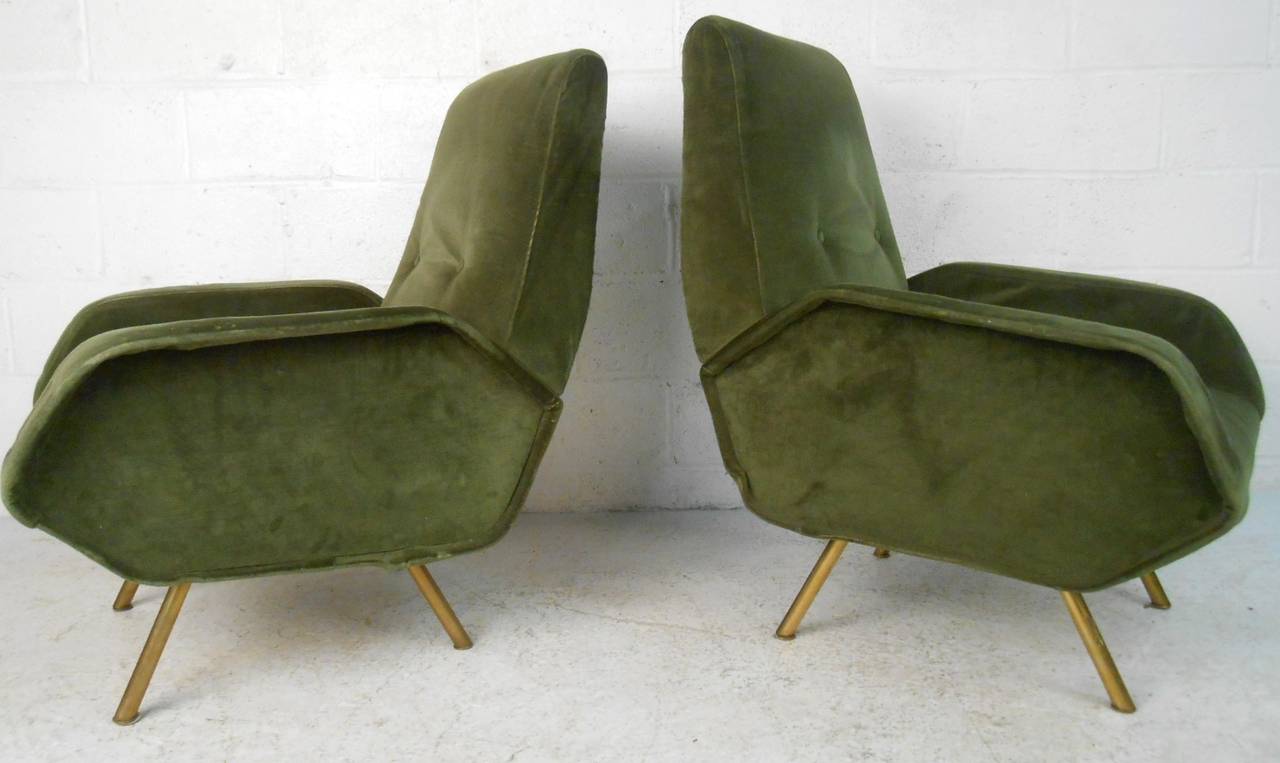 This beautiful pair of matching Mid-Century armchairs make a comfortable and stylish addition to any interior space. Unique sculpted arms, tufted seat backs and angled brass legs add to the wonderful aesthetic of the pair. Please confirm item