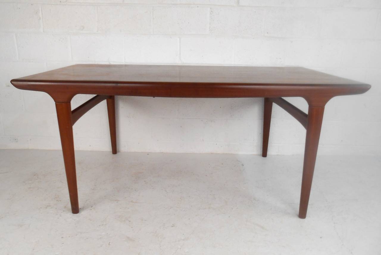 This unique Danish teak dining table features an expandable leaf, adding plenty of room for additional seating and serving. Uniquely sculpted edges and tapered legs add to the visual appeal and make this a great choice for any room in need of