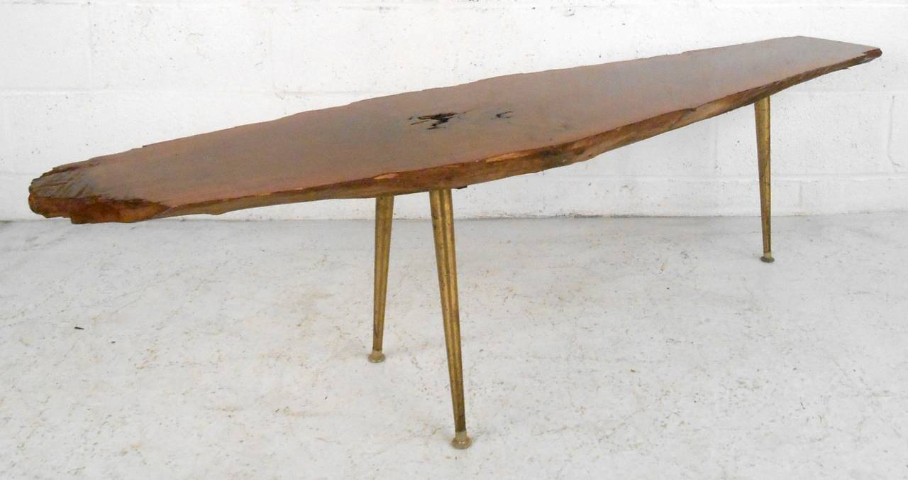 Unusual coffee table with three brass legs and a live edge finish. Distinct with natural knot exposed, free edges and tapered brass legs.

(Please confirm item location - NY or NJ - with dealer).