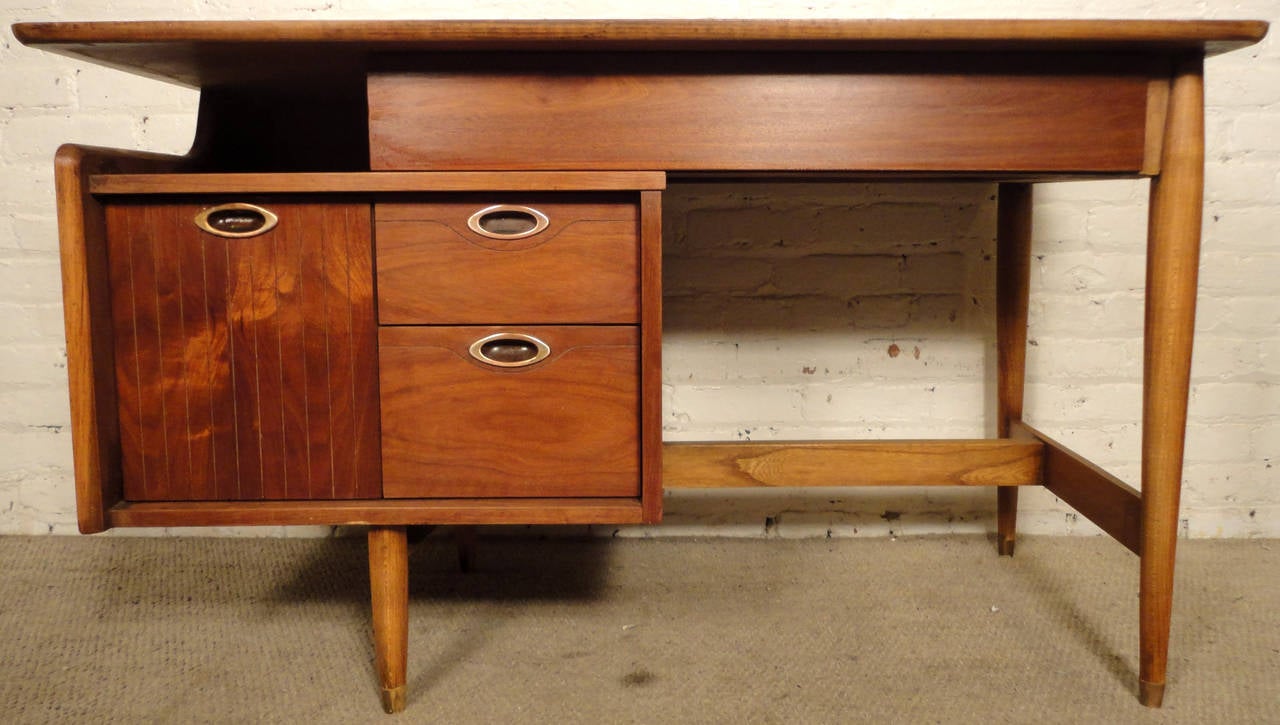 Walnut mid century American desk by Hooker for their Mainline collection. Featuring three drawers on left side with single middle drawer, sculpted pulls and tapered legs. Please confirm item location (NY or NJ) with dealer.