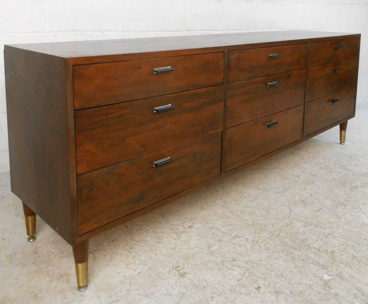 This substantial rosewood dresser features sturdy construction, leveling brass feet, and unique mid-century modern drawer pulls. Rich woodgrain, vintage Harvey Probber style, and plenty of storage make this a wonderful addition to any home or