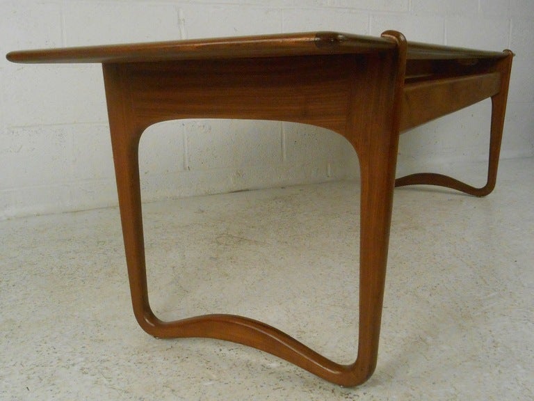 Teak coffee table by Peter Hvidt & Orla Molgaard Nielsen features unique sculpted frame and iconic Scandinavian modern design. A scrumptious Danish modern addition to home or business seating area.  Please confirm item location (NY or NJ) with