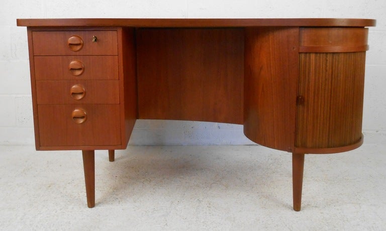 Teak, kidney shaped desk by Kai Kristiansen, c.1955. Tambour door with lazy-susan storage on right, circular secret storage above, three drawers on left and bookshelf on rear side. Please confirm item location (NY or NJ) with dealer.