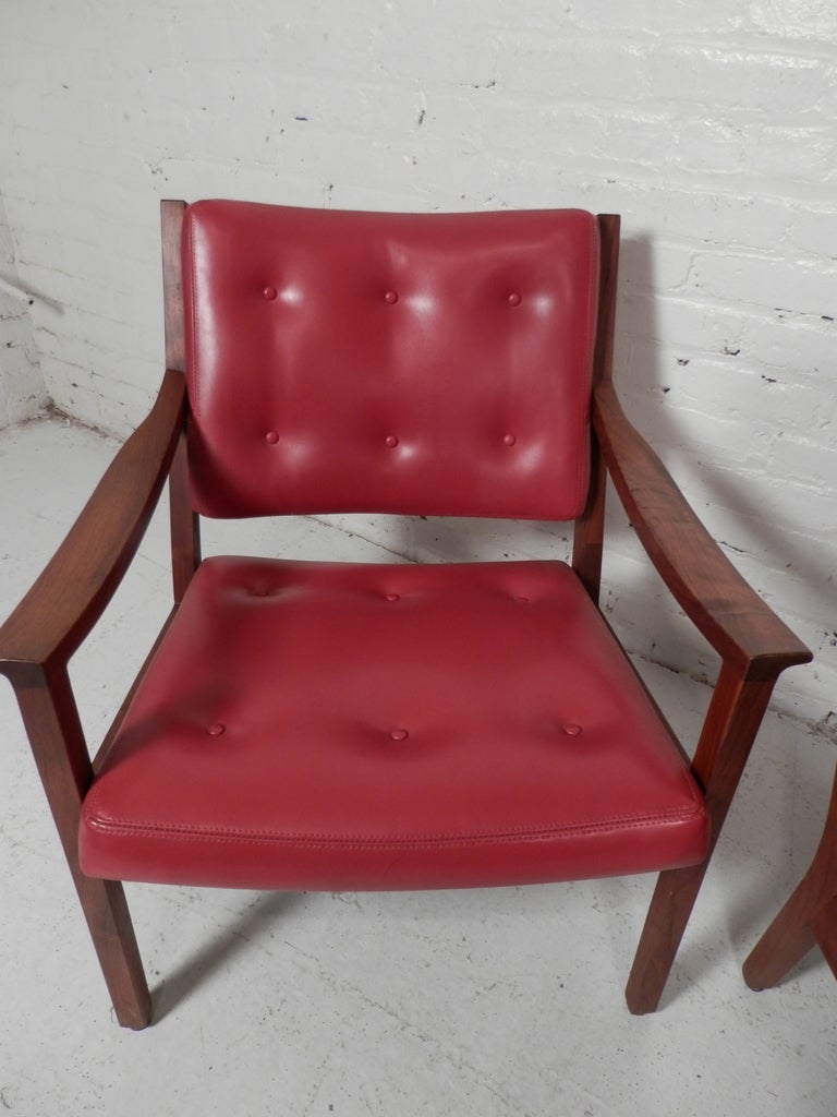 Pair of walnut frame chairs with tufted vinyl seats. These are extraordinarily well made by one of the most respected manufacturers in the country, in business since 1902. Simple, modern design with contoured seats and flared arm rests.

(Please