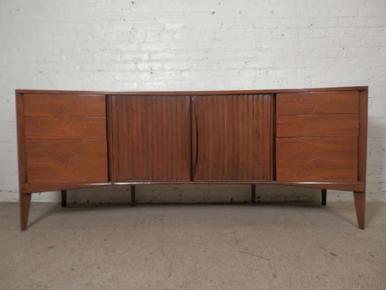 Unusual curved front nine-drawer long dresser with louvered doors and sculpted handles. Great vintage design with interesting lines, bountiful storage and elegant tapered legs makes a striking addition to any interior, bedroom or otherwise!

(Please