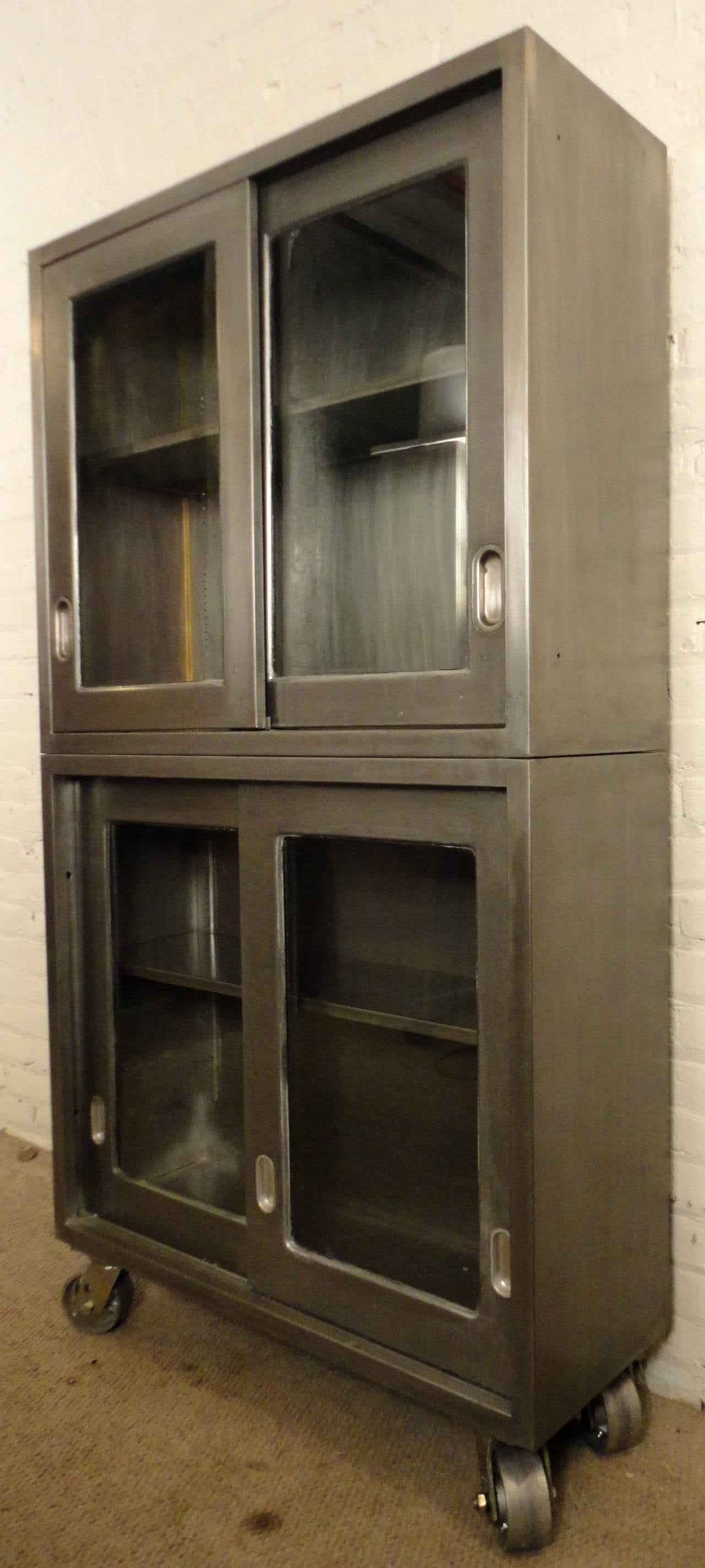 Large Industrial metal cabinet set on 360 degree castors. Features sliding glass paneled doors and two adjustable shelves. Unique unit that works great in the kitchen or living room.

(Please confirm item location - NY or NJ - with dealer).