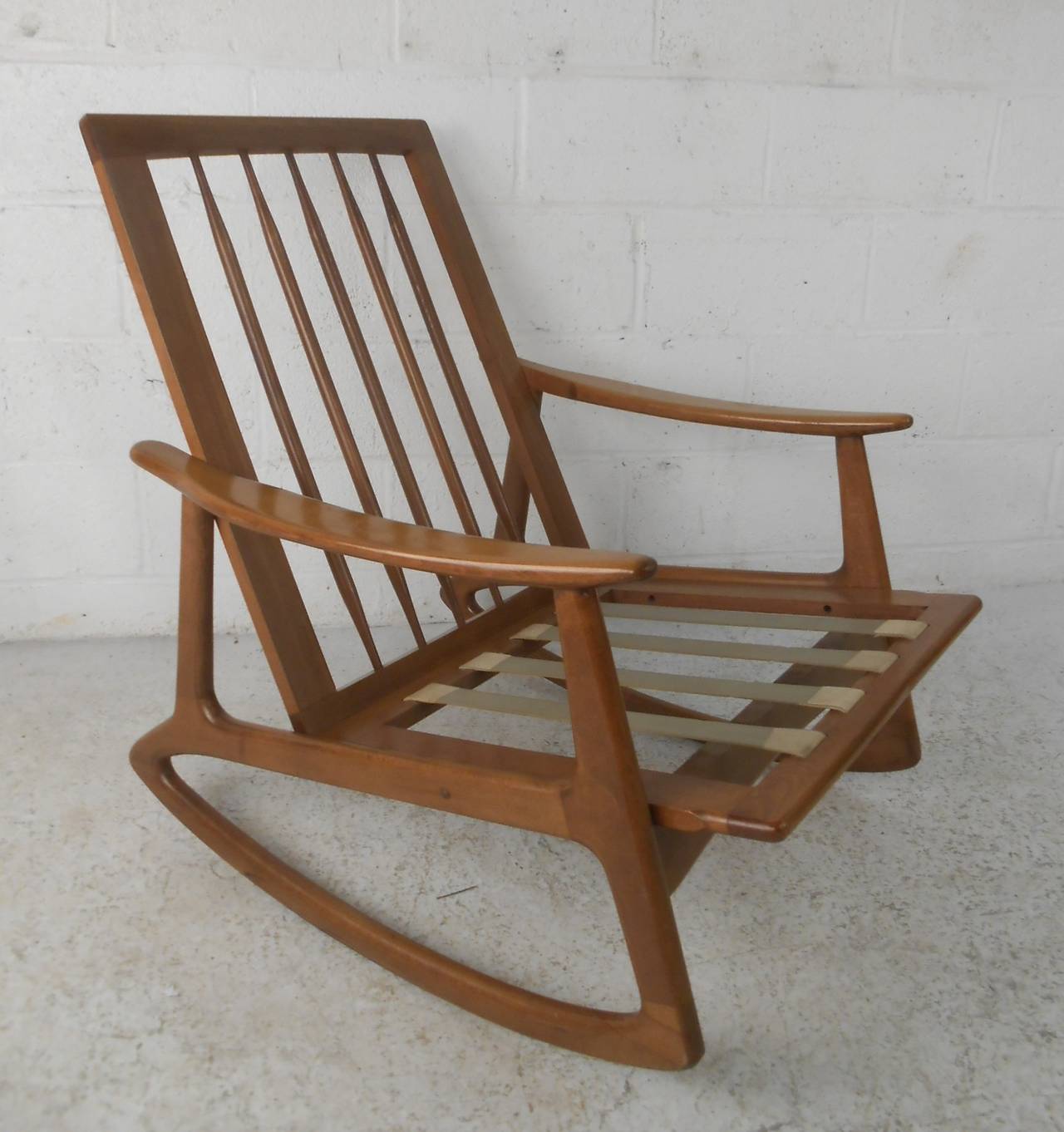 Classic Mid-Century Modern rocking chair in walnut. Stylish and comfortable, this chair is ready for updated upholstery and perfect for any interior. Please confirm item location (NY or NJ) with dealer.