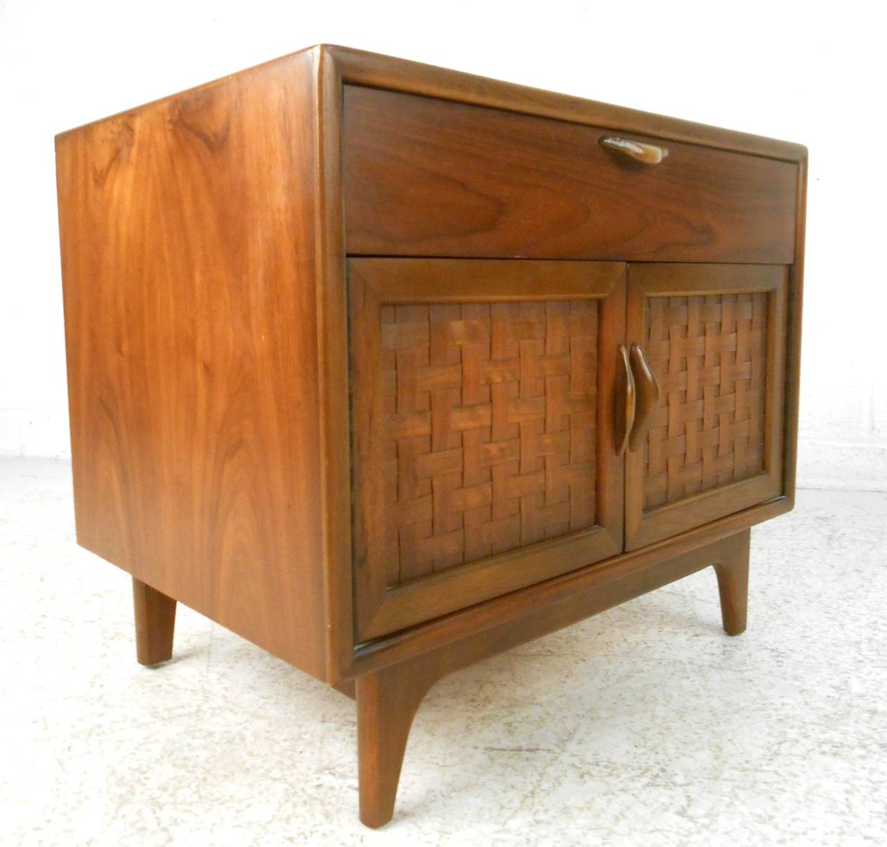 This single walnut nightstand features the unique basket weave front made popular by the designer in the 1960s. Combination of cabinet and drawer storage, this piece is perfect for use in any setting. Please confirm item location (NY or NJ).