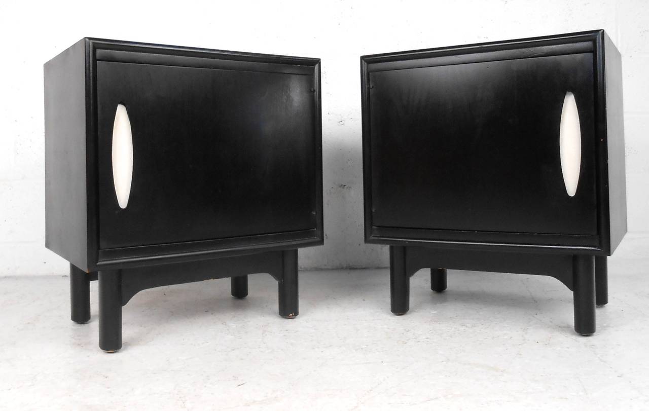 This pair of matching Mid-Century nightstands feature mirrored cabinet doors which conceal open storage for any bedside necessities. Unique cut-out door pull and monochrome paint job make these an eye-catching set. Please confirm item location (NY