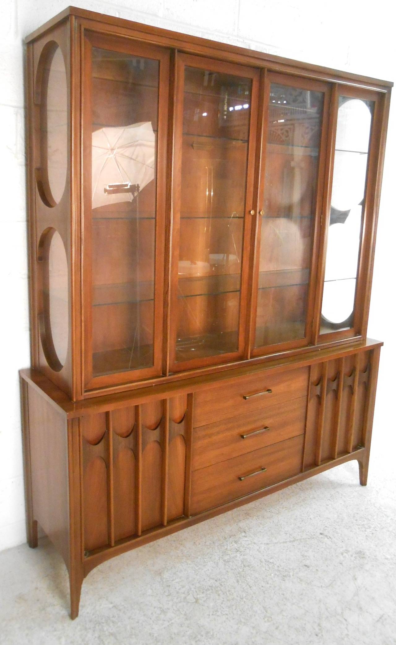 This matching two-piece server with display hutch makes for an elegant addition to any dining area. Iconic Kent Coffey design includes sculpted cabinets, tapered legs, and spacious glass display shelves all combine to make this a striking vintage