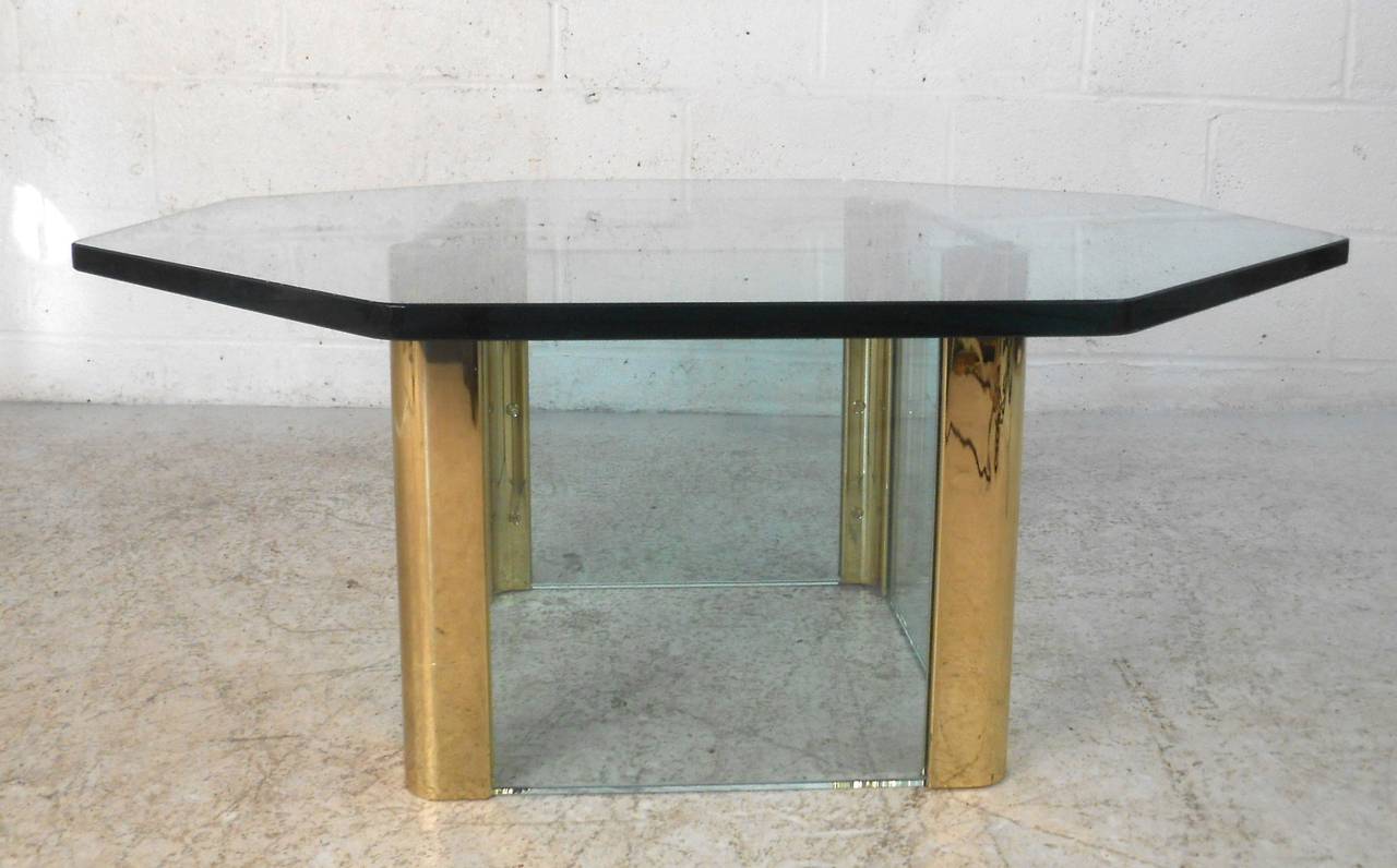 This unique Pace style mid-century coffee table features a simple yet striking glass and brass base. The sturdy and substantial Leon Rosen style design of this base comfortably supports a thick octagonal glass top. Please contact dealer for item