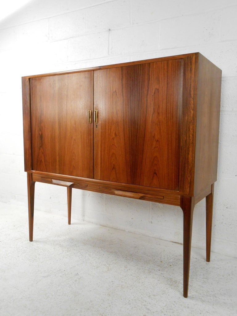 Rosewood bar cabinet by Illum Wikkelso and made by C.F. Christensen, Denmark. Tambour doors, two drawers, glass shelf, diamond frosted mirrors, internal light and two pull-out shelves for mixing drinks. Please confirm item location (NY or NJ) with