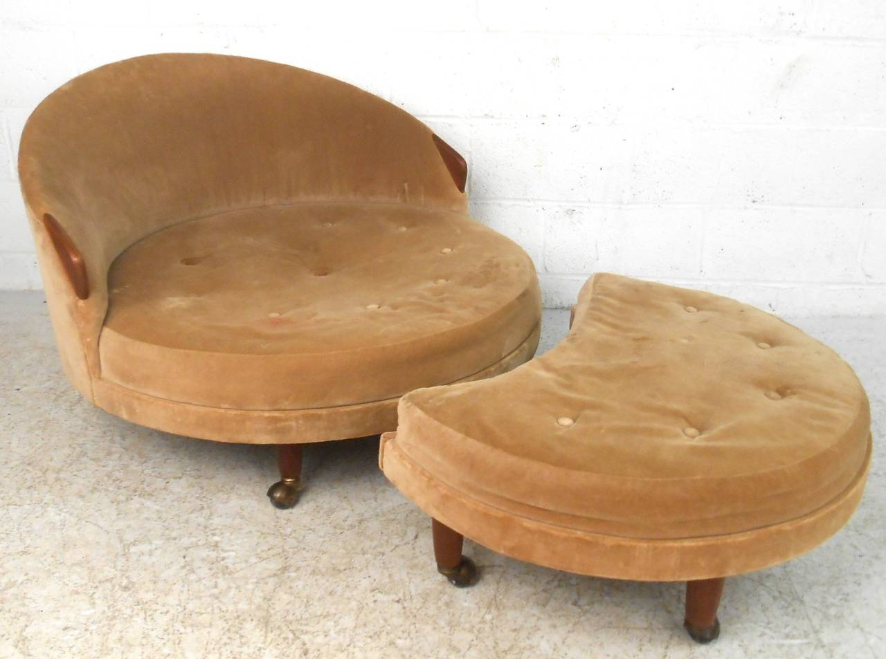 This matching mid-century lounge chair and ottoman features unique hardwood armrests and legs, and our both mounted on sturdy casters. Unique design brings wonderful modern style to any setting. Please confirm item location (NY or NJ).