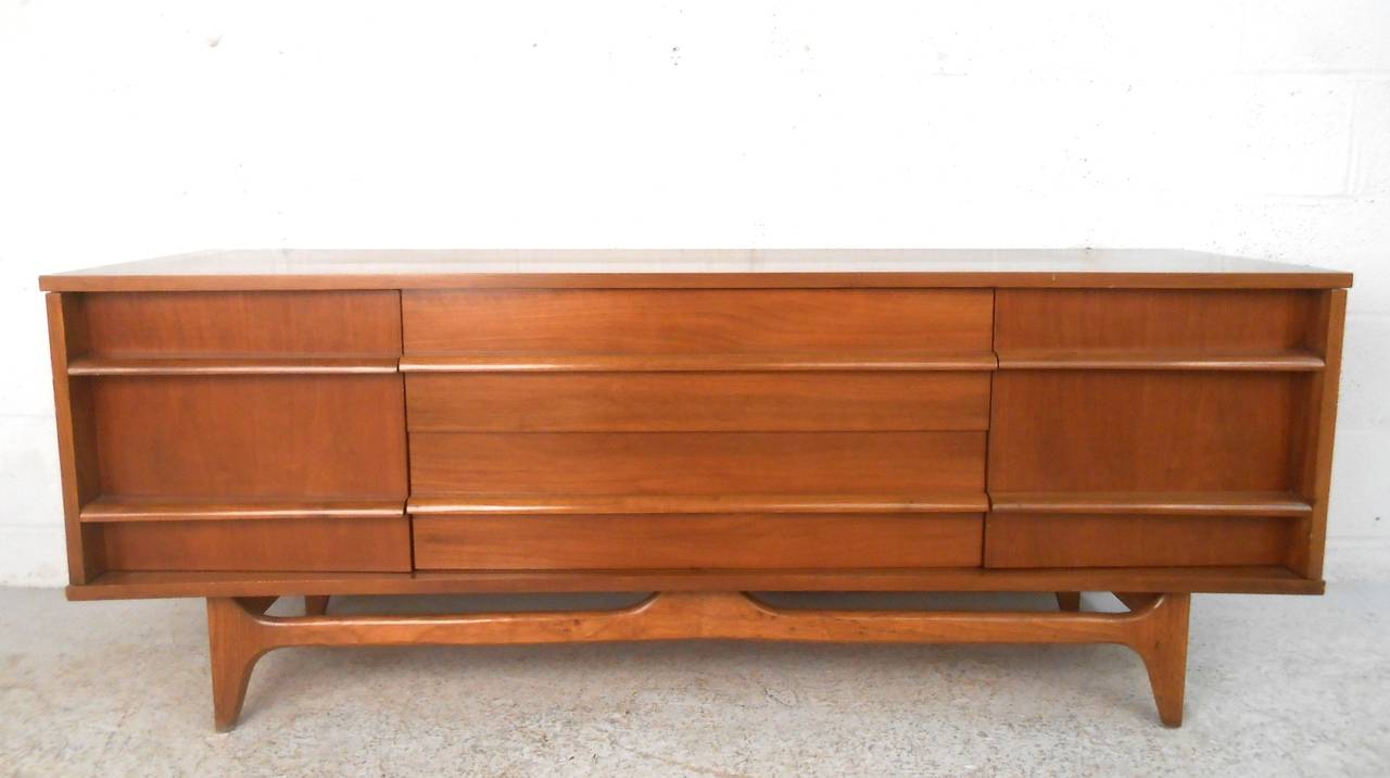 This uniquely sized long & low curved front credenza features a curved front, and several storage options in the form of dual cabinets and drawers. Fantastic addition to any setting as a low credenza or TV console, unique stretcher and tapered legs