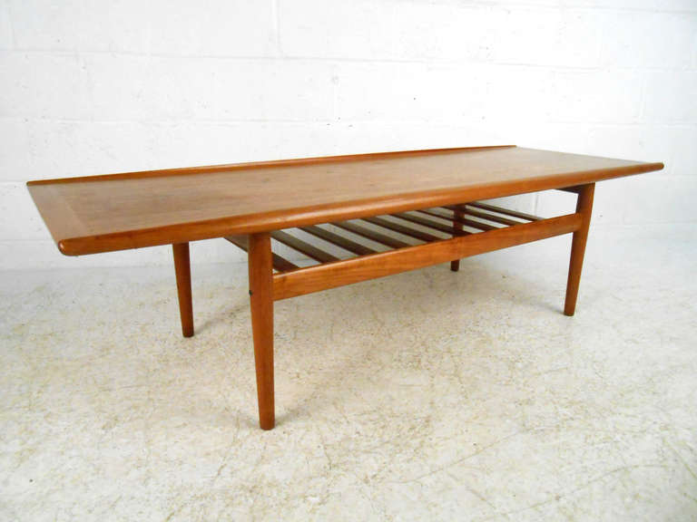 This Danish mid-century modern teak coffee table features the beautiful design of Grete Jalk. Wonderful lines and unique raised edges make this the perfect piece for home or business. Danish Furniture Makers Control label. Please confirm item