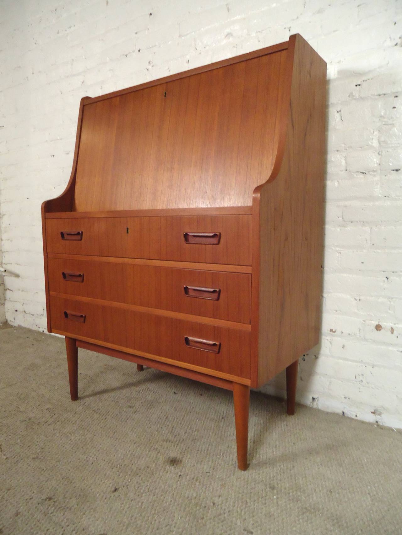 Mid-century modern drop front secretary desk with drawers. Beautiful teak grain throughout, nicely sculpted handles and tapered legs. The top comes down for a surface area of 32