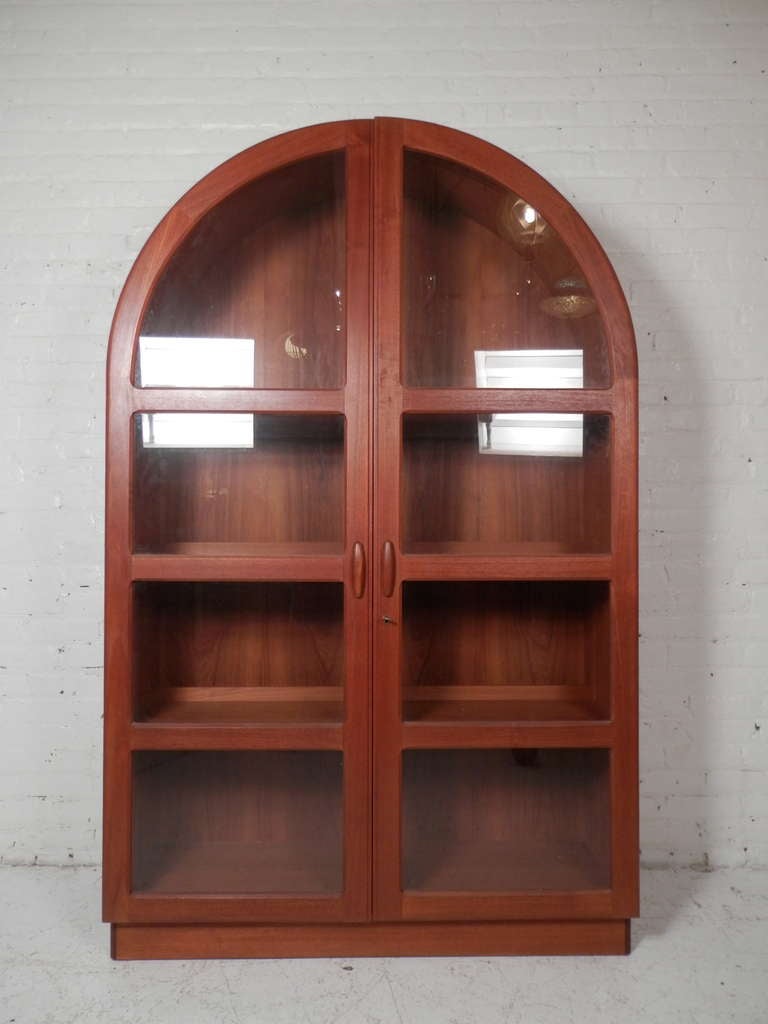 Vintage Danish modern cabinet with glass doors made by Dyrlund. Rounded top, carved handles, key lock. Three separately controlled lights add to this beautiful teak piece.

(Please confirm item location - NY or NJ - with dealer)