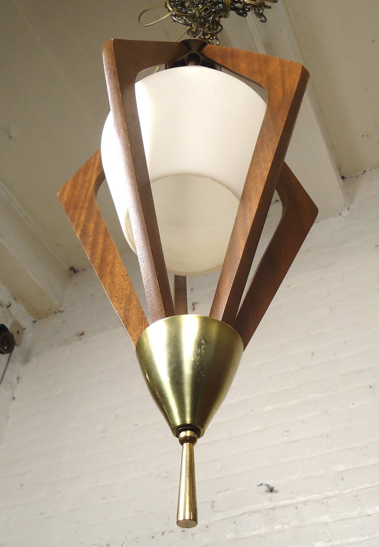 Angular vintage modern hanging pendant with milk glass shade and sharply sculpted walnut frame. Accented with brass trimming.

(Please confirm item location - NY or NJ - with dealer)