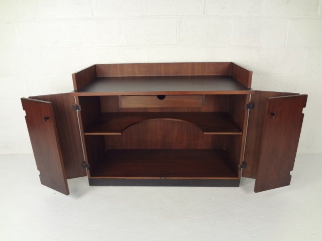 Mid-century walnut bar with bi-fold doors, casters, iron hardware, and black laminate work surface. 

Please confirm item location (NY or NJ) with dealer.