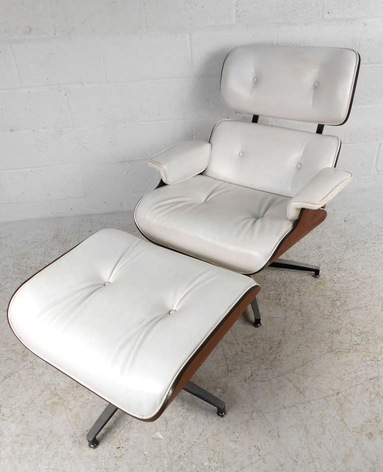 This classic Eames-style design combines stylish design with incredible comfort. With tufted white vinyl and a striking walnut shell this matching chair and ottoman make a wonderful addition to any home. Please confirm item location (NY or NJ).