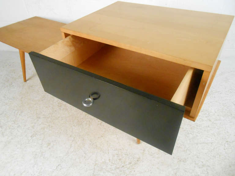 This McCobb coffee table/bench features a unique moveable single drawer cabinet, tapered legs, ring style drawer pull, and maple finish. 
Please confirm item location (NY or NJ)